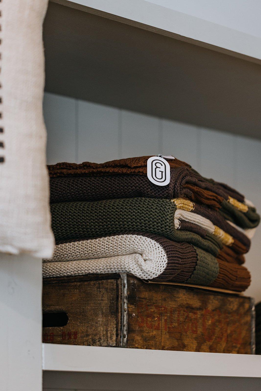 Folded wool and linen throws stacked on an antique wooden chest