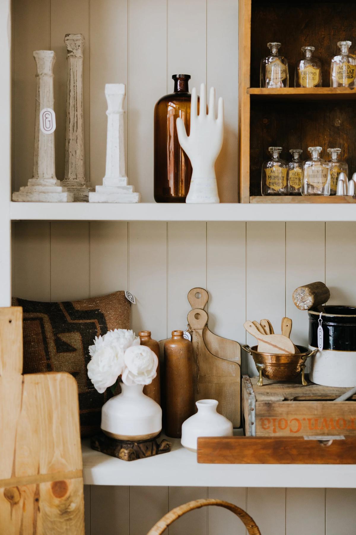 Ceramic vessels and apothecary bottles on a white painted shelf